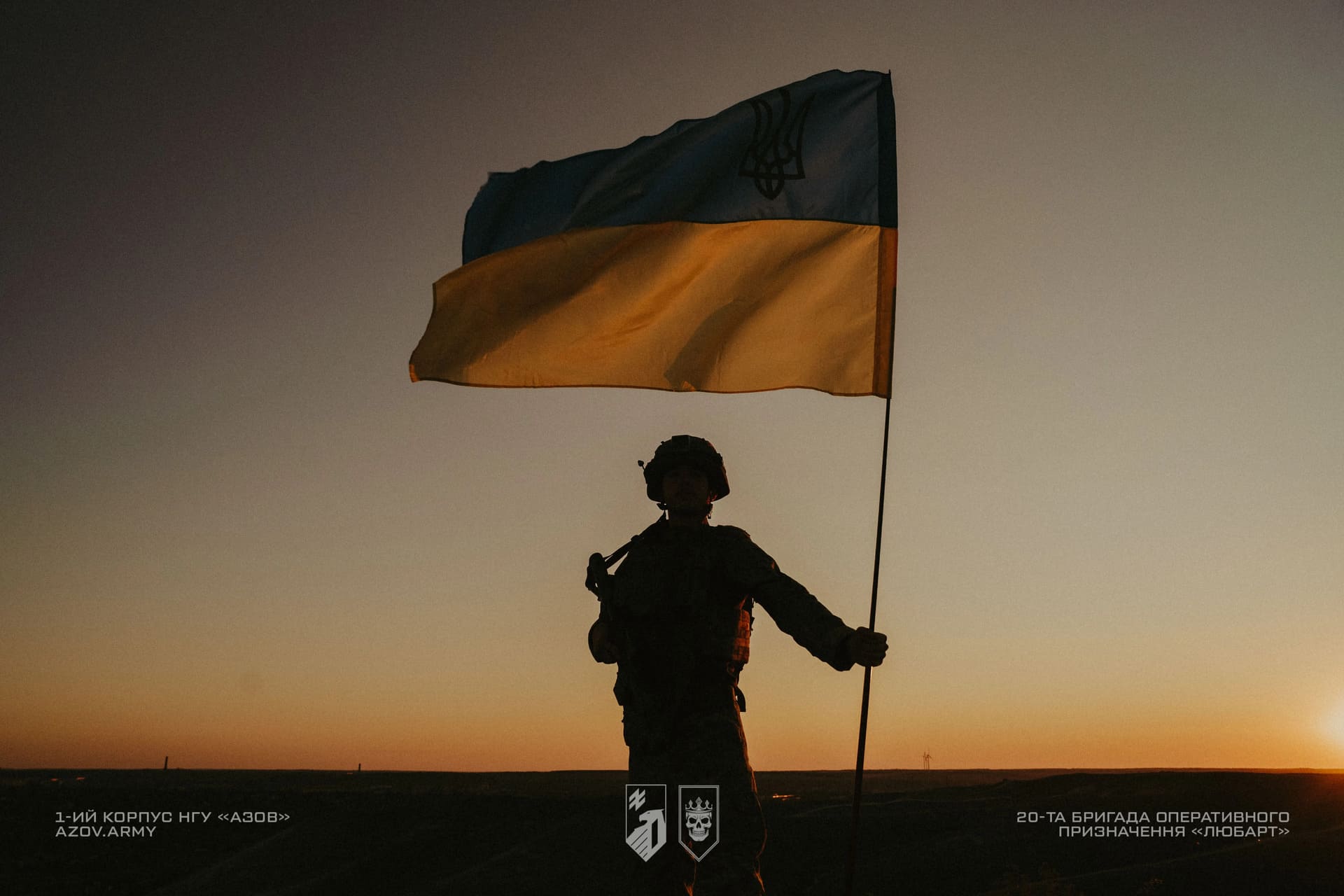 Боєць бригади Любарт тримає в руці прапор України на заході сонця