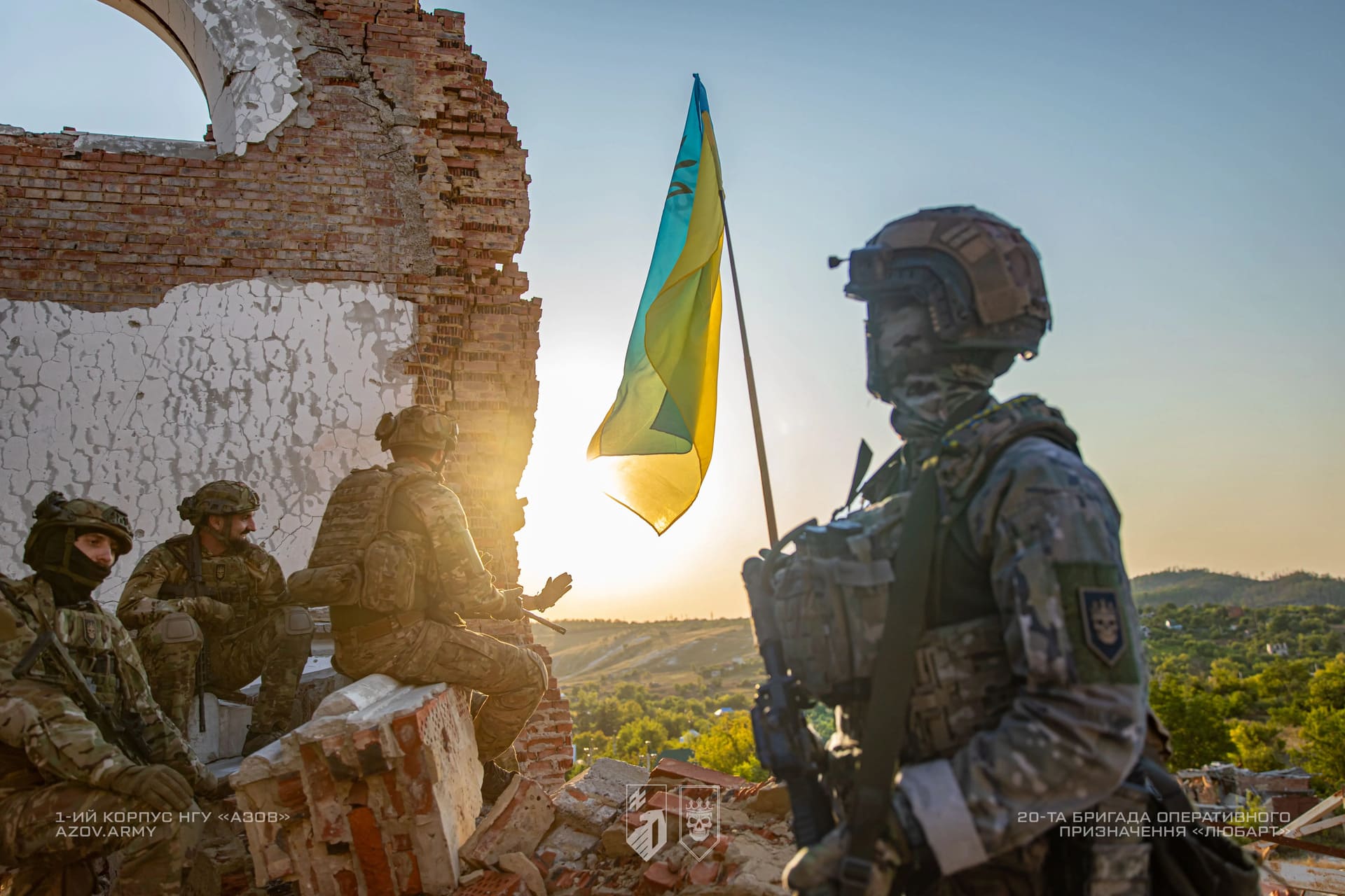 Бійці бригади Любарт на фоні руїн будинку та українського прапору