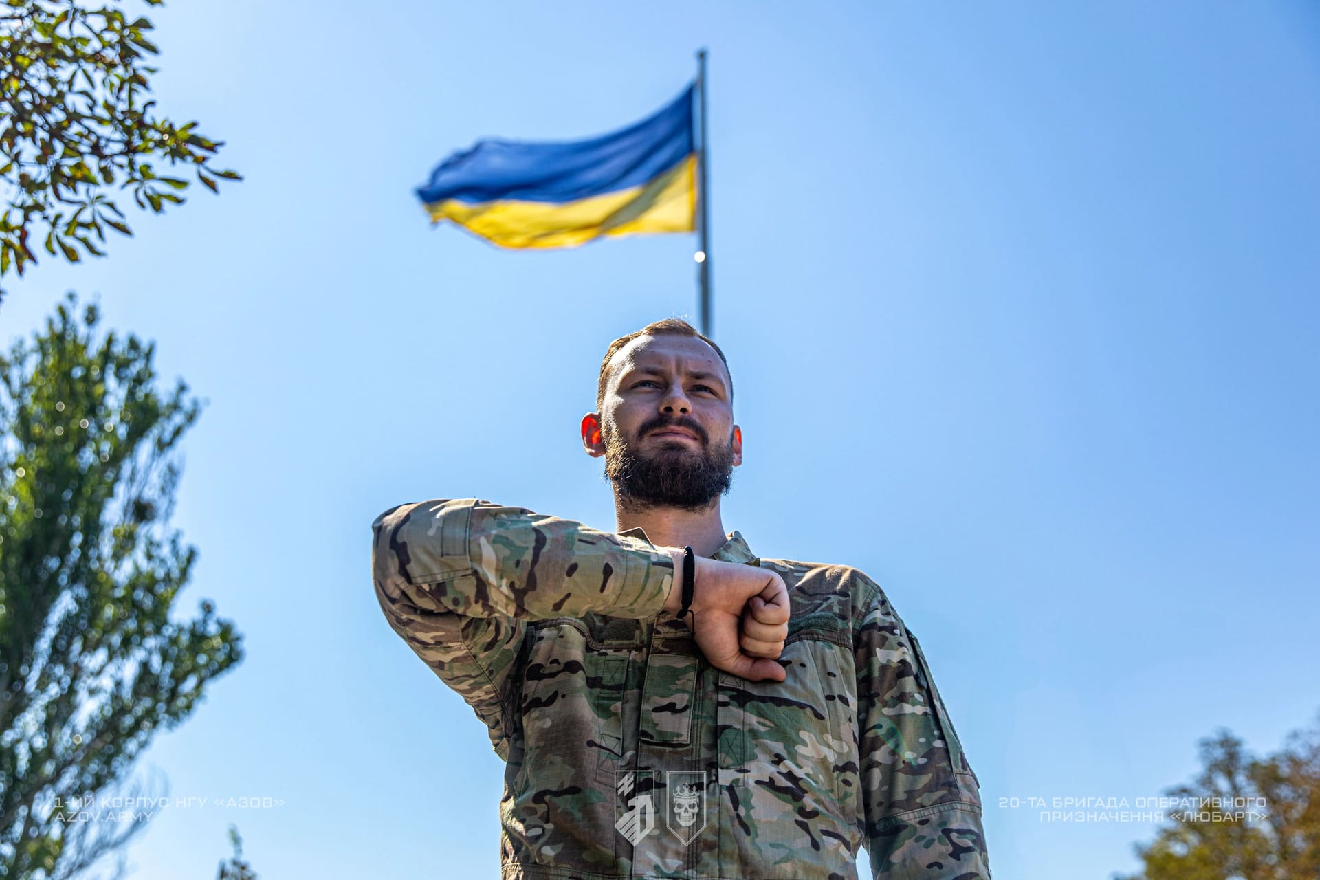 Боєць бригади Любарт віддає честь на фоні українського прапору
