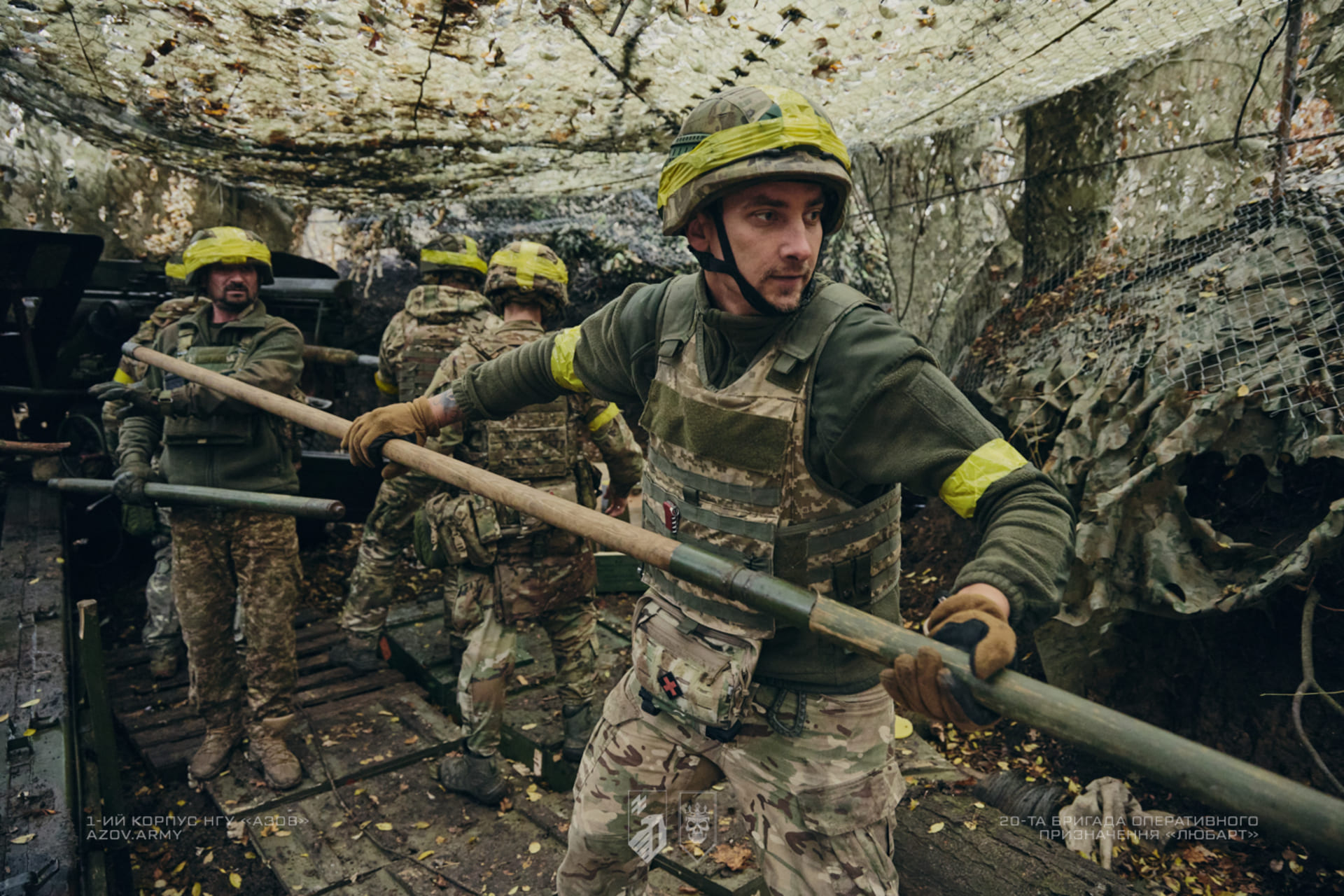 Артилеристи споряджають артилерійську установку під маскувальною сіткою