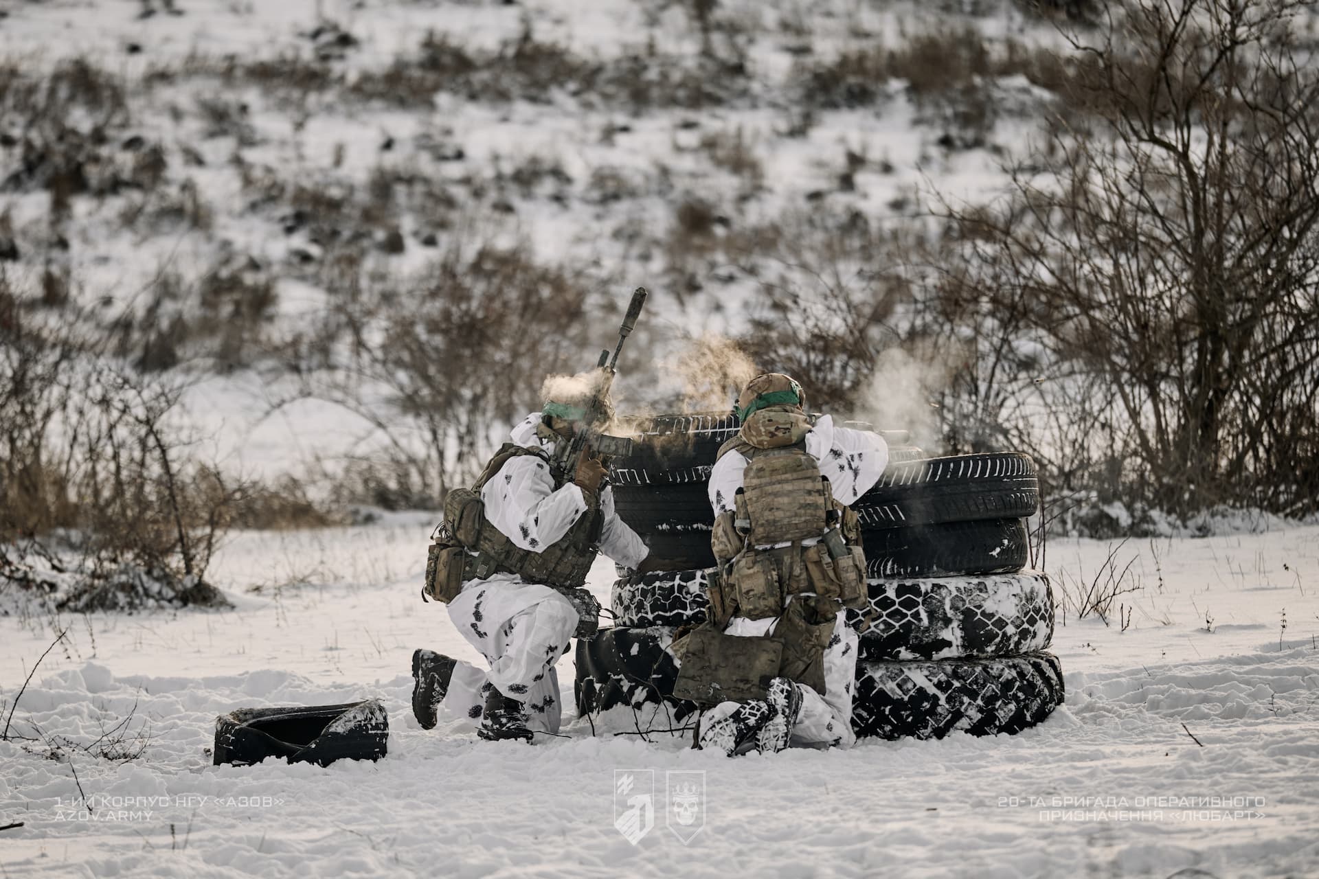 Двоє військовослужбовців в зимовому екіпіруванні за укриттям на полігоні