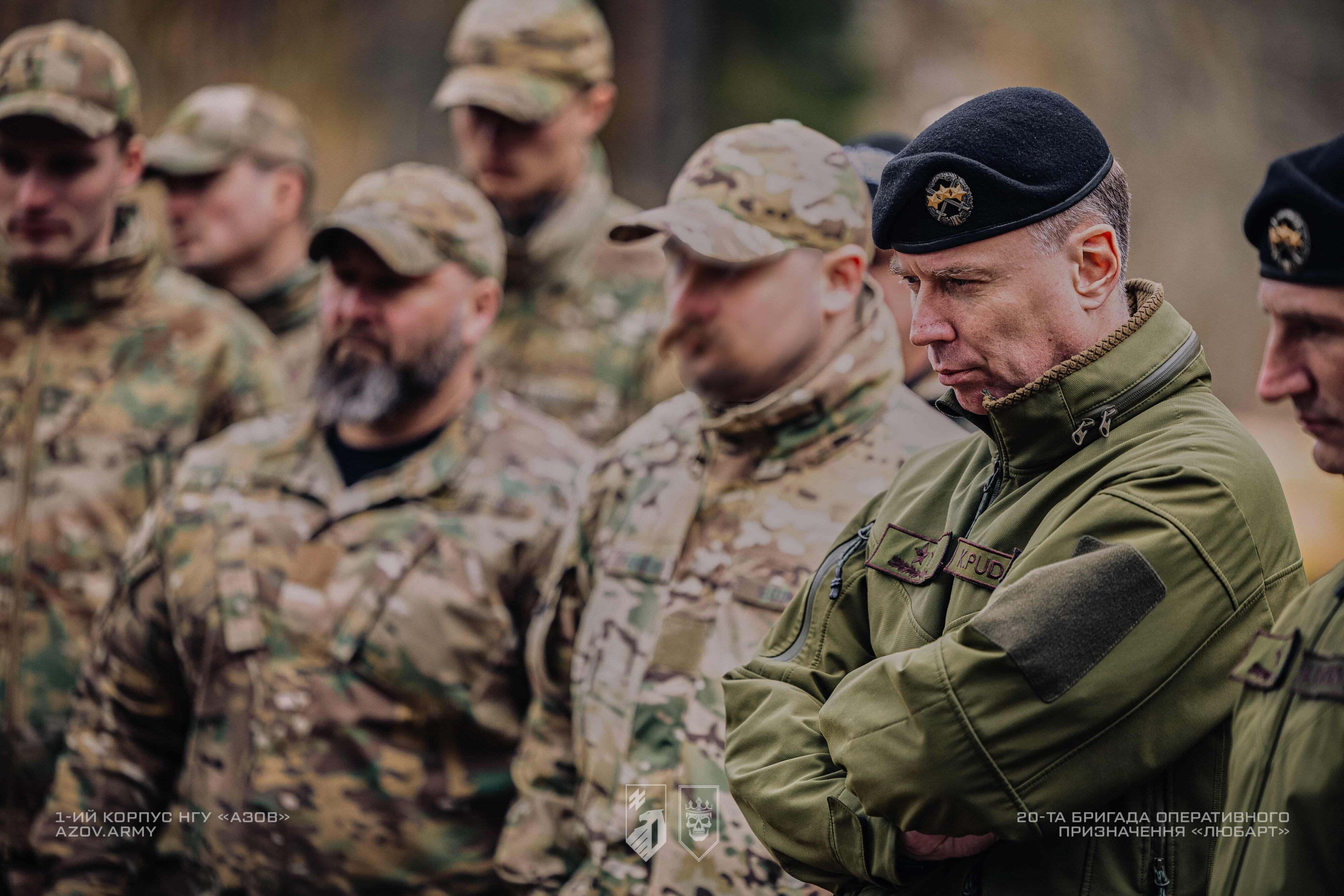 військовий у береті слухає брифінг разом з іншими військовими